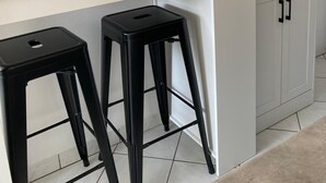 A kitchen with a microwave, an oven, a digital clock, and two black stools. - Appt 55m², 4-5 pers, 100m beach, parking, adult bike hire, WIFI (Quiberon)