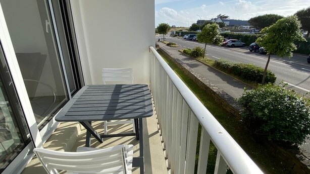 A balcony with a table and chairs, overlooking a street with parked cars and greenery. - Appt 55m², 4-5 pers, 100m beach, parking, adult bike hire, WIFI (Quiberon)