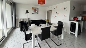 A modern dining area with a white table, black chairs, and a red pendant light. - Appt 55m², 4-5 pers, 100m beach, parking, adult bike hire, WIFI (Quiberon)
