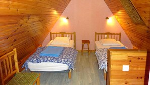 A small, cozy attic bedroom with two wooden beds, a small stool, and a wooden bench. - Chalet''Le Chardon '' 67m2 + 20m2 rental from 2 to 7 people with modular option (La Bourboule)