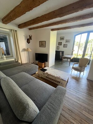 A living room with a sofa, a coffee table, a television, and a dining area with a chair. - House, Veyrier du Lac close to the Lake and daily shopping. (Veyrier-Du-Lac)