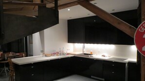 Une cuisine moderne avec des meubles de couleur sombre, un plan de travail blanc et un évier en acier inoxydable.