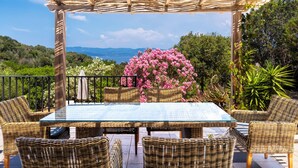 An outdoor patio with wicker furniture, a glass table, and a view of the landscape. - Beautiful villa with pool, sea view, large garden and beach 7mn walk to Campomoro (Belvédère-Campomoro)