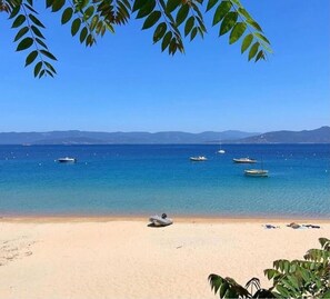 A beach with clear blue water, several boats, and a sandy shore.