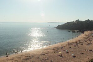 Une plage où l’on peut se prélasser au soleil et se baigner, un littoral rocheux et un ciel dégagé.