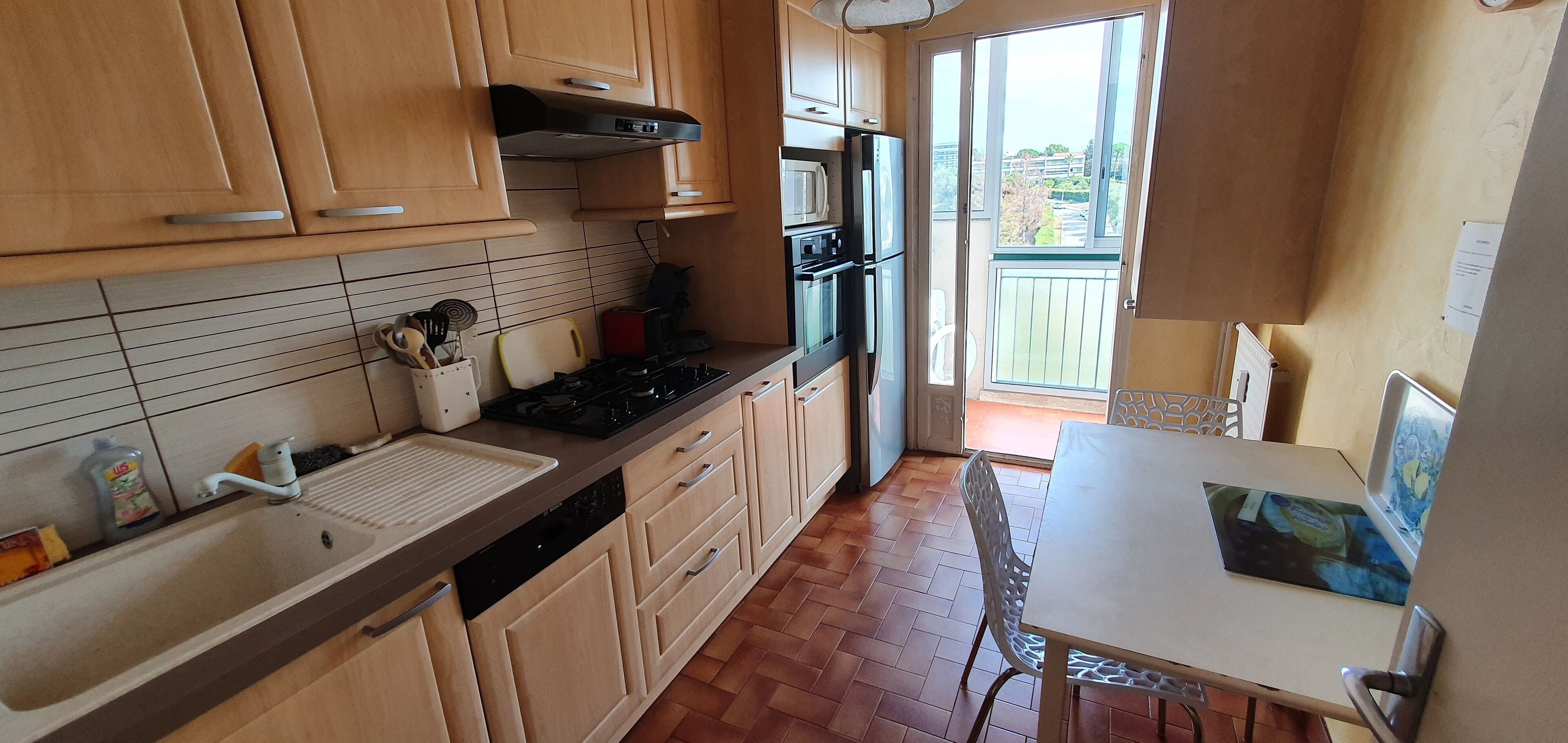 Une cuisine dotée de meubles en bois, d’un évier, d’une cuisinière et d’un coin repas avec une table et des chaises.