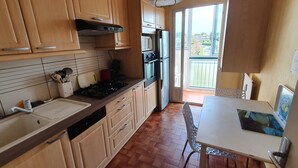 Una cocina con armarios de madera, un fregadero, una estufa y una zona de comedor con mesa y sillas.