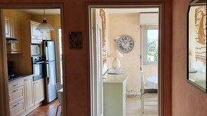 Una cocina con electrodomésticos modernos, un comedor con mesa y sillas, y un reloj de pared.