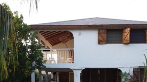 A two-story house with a covered porch and a garage. - Maisoson 130m in Sainte-Rose for the holidays at the seaside, mountains. (Sainte-Rose)