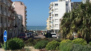 Una calle costera con edificios, un pavimento adoquinado y un cielo azul despejado.