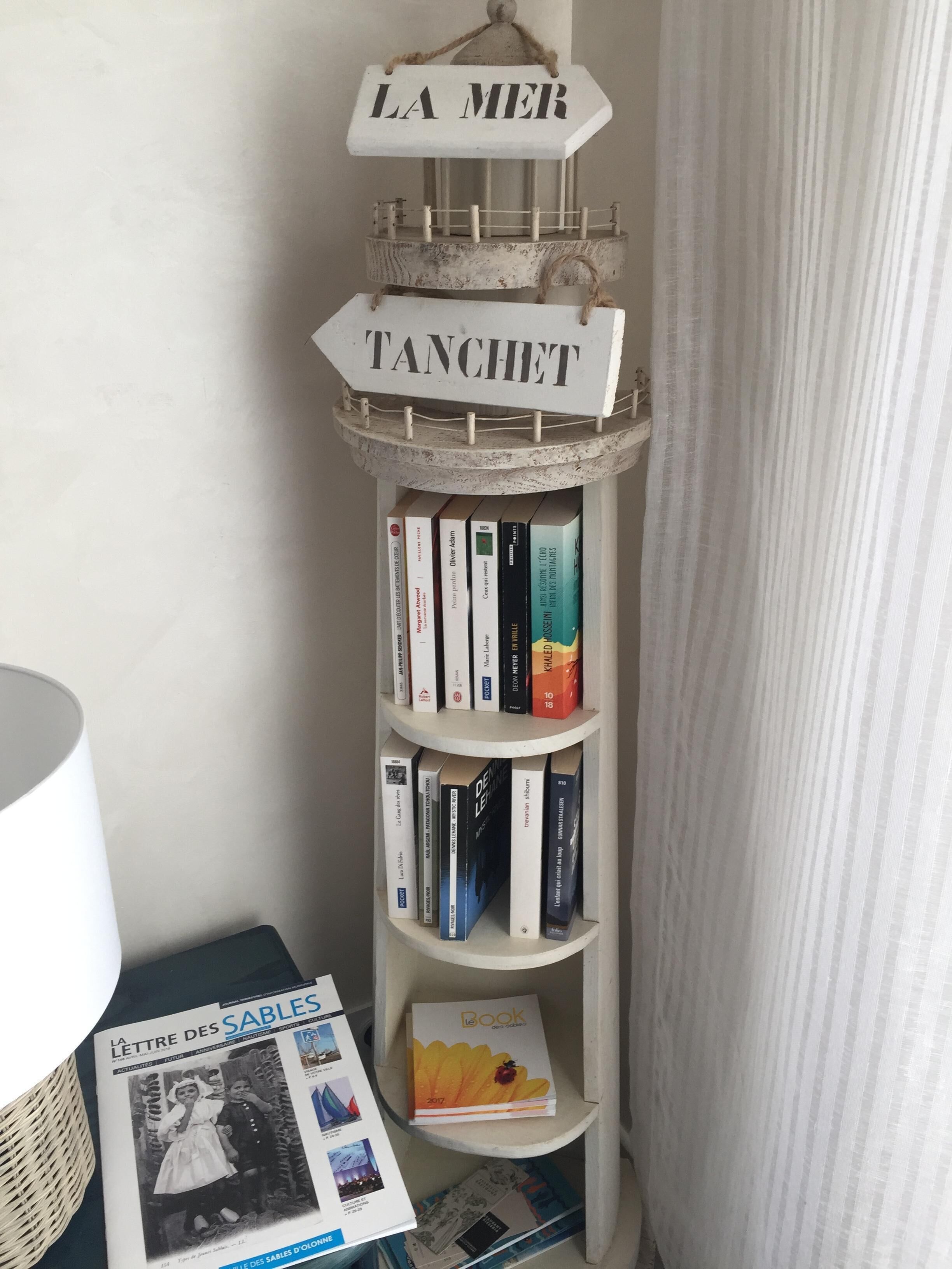 Une bibliothèque remplie de livres et une pancarte sur laquelle on peut lire : « LA MER TANCHIET ».
