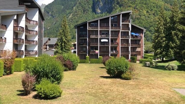 Un hotel de varios pisos, con balcones y montañas al fondo.