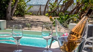 A poolside setting with a bottle of champagne, two glasses, and a chair. - La Régence (Le Diamant)