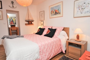 Een slaapkamer met een bed, nachtkastjes, een hanglamp en kunst aan de muren.