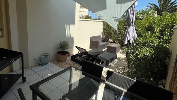 A sunlit patio with a glass table, black wicker chairs, and a white shade sail. - Les Goëlettes apartment in Saint Cyprien Plage, Pyrenees - Orientales - 4 people (Saint-Cyprien)