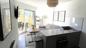 A modern kitchen with a large island, a dining area with a table and chairs, and a living room with a sofa and a TV mounted on the wall. - Les Goëlettes apartment in Saint Cyprien Plage, Pyrenees - Orientales - 4 people (Saint-Cyprien)
