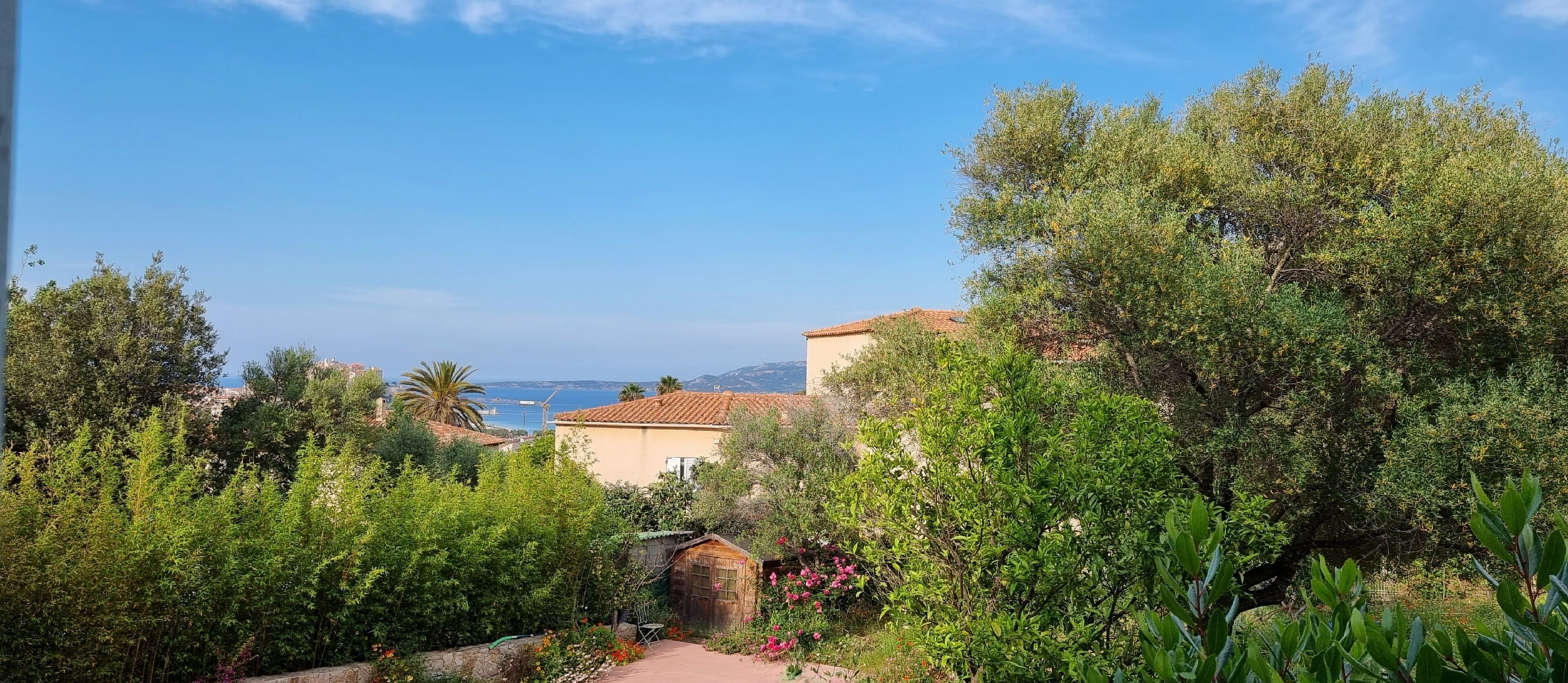 Un jardin avec un sentier menant à un bâtiment doté d’un toit en tuiles.