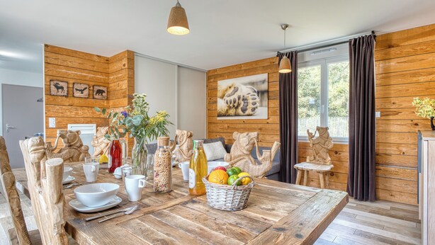 Una mesa de madera con sillas, una cesta de frutas y varios objetos decorativos.