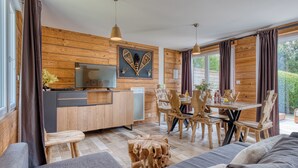 Interior de madera con comedor, sofá, televisor y detalles de madera.