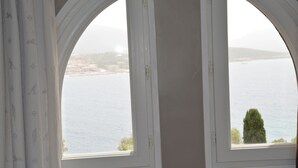 A room with two arched windows overlooking a body of water and a distant landscape. - Villa A LISCIA Marinca (Olmeto)