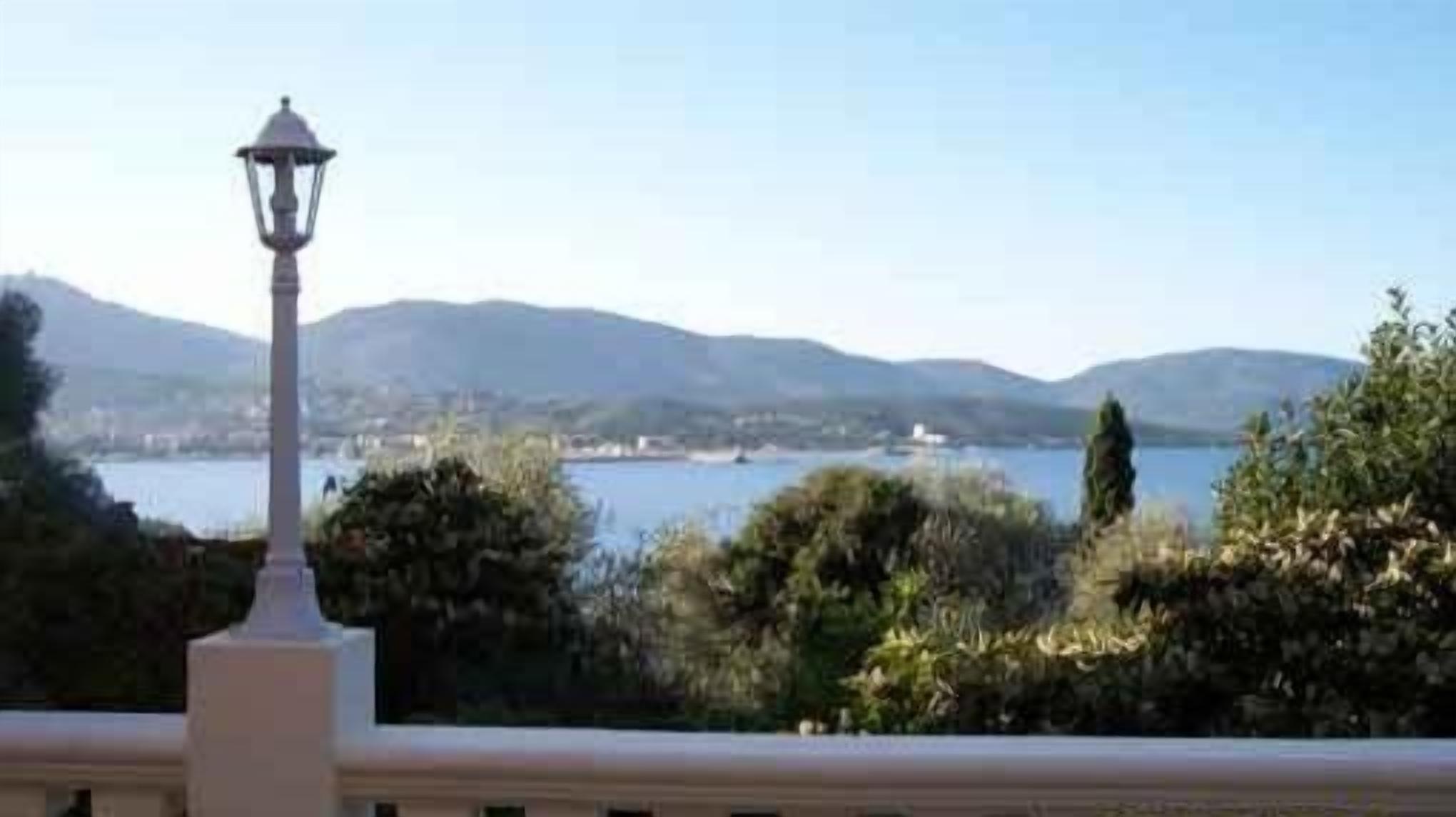 Un balcón con un farol que da a un lago y colinas.