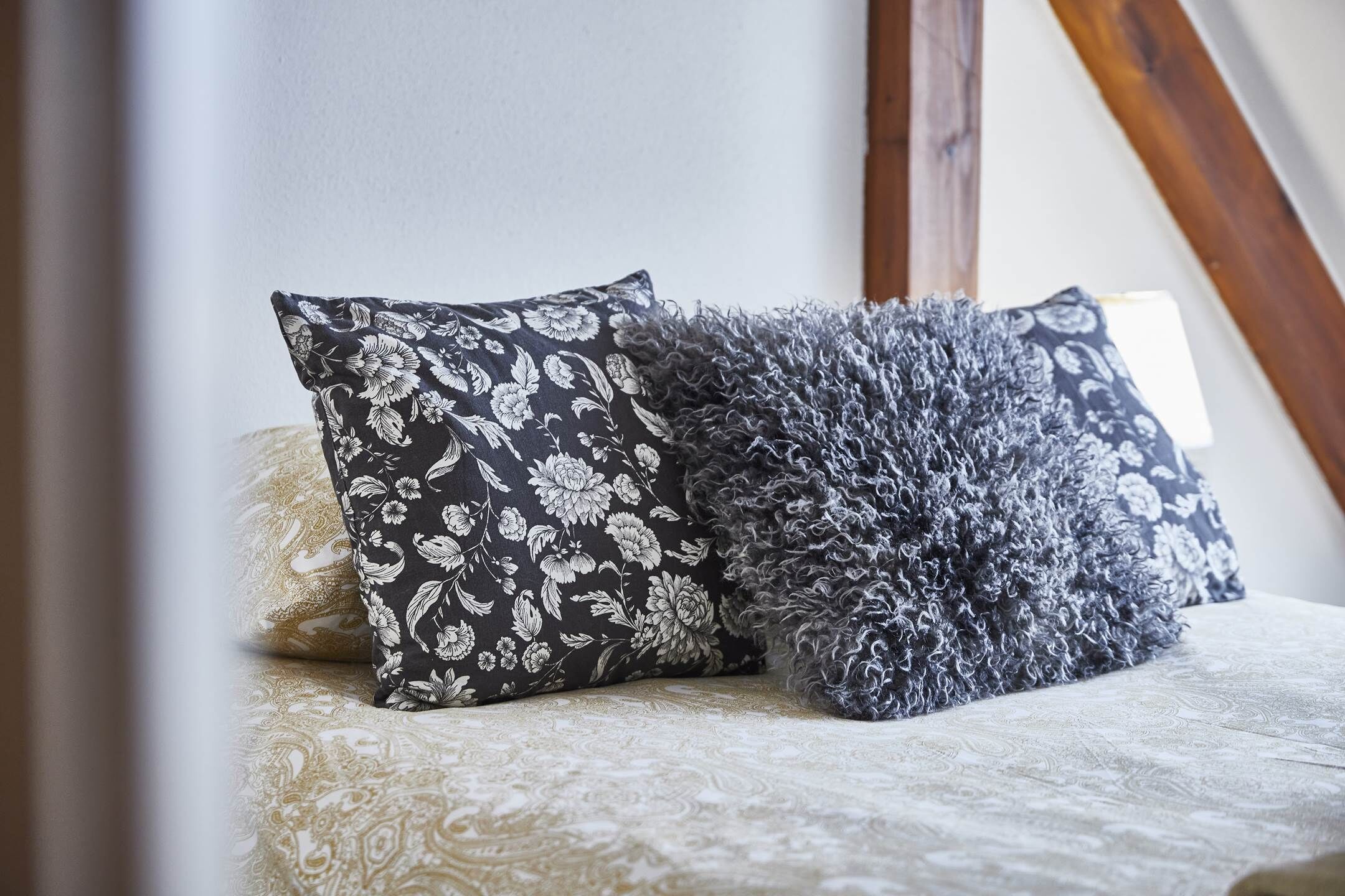 Ein Bett mit zwei Kissen, eines mit Blumenmuster und das andere flauschig.