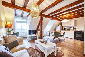 A spacious loft with a high ceiling, exposed wooden beams, a dining area, and a kitchen. - Cosy gîte in winegrower's house - Ophélia 3 persons (GERTWILLER)
