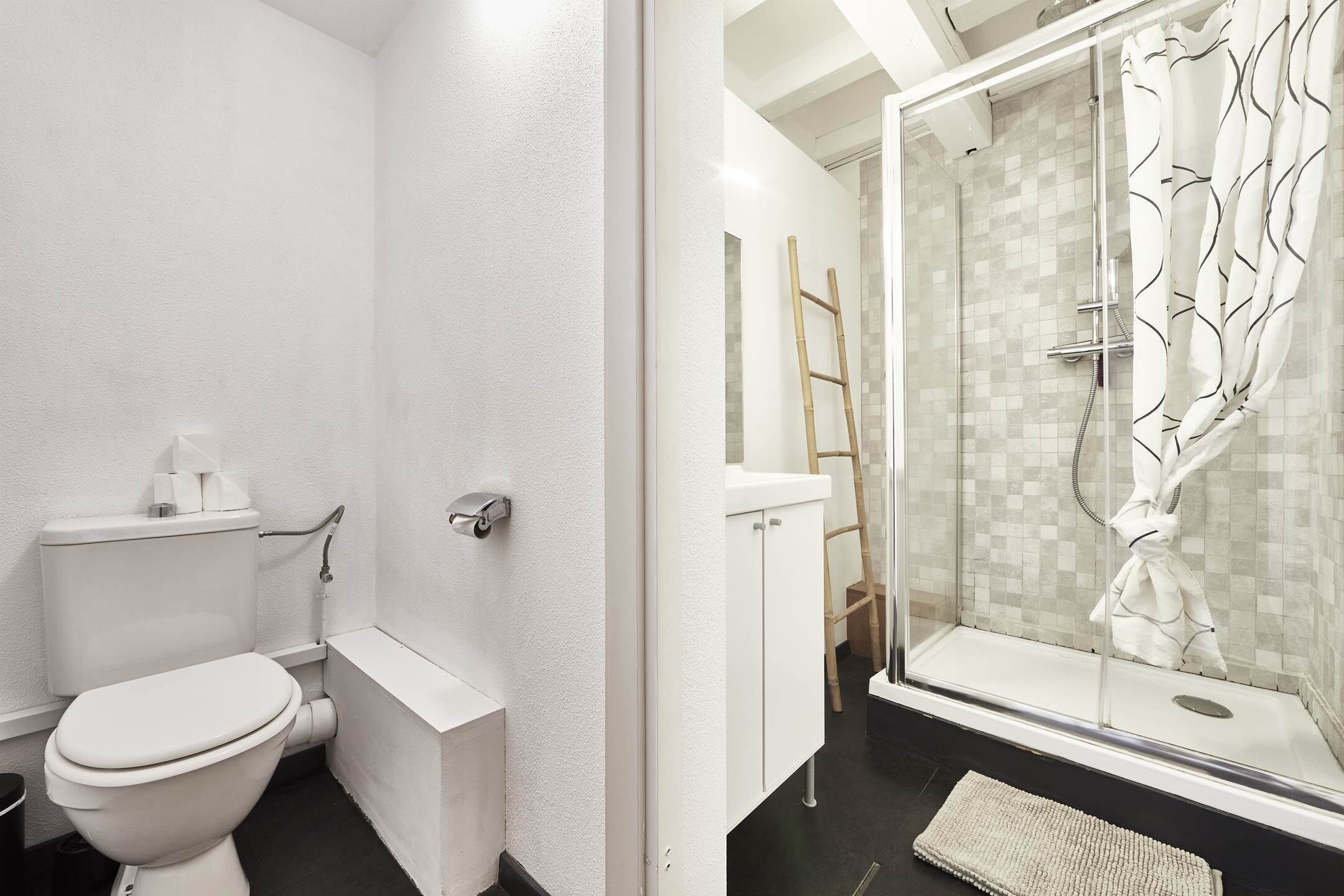 Et badeværelse med toilet, håndvask og brusekabine med glasvægge.