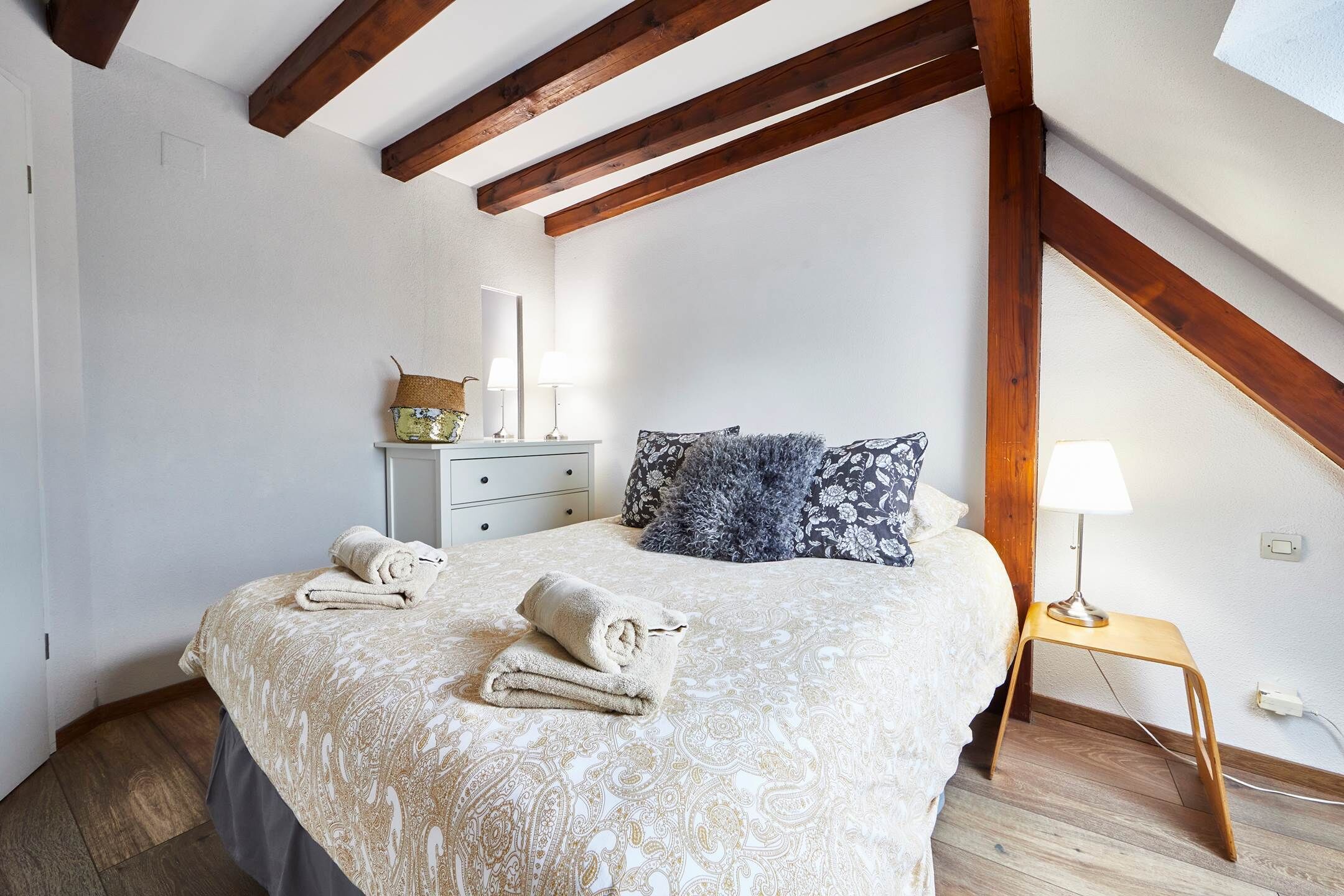 Ein Schlafzimmer mit Bett, Nachttisch, Lampe und Kommode.