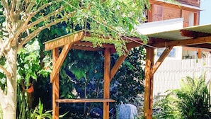 Un jardin avec une pergola en bois, un barbecue et des plantes en pot.