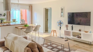 Un salon moderne comprenant un canapé, une table basse, un téléviseur et un coin repas avec des chaises et une table.