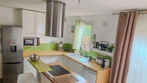 Une cuisine compacte équipée d’un réfrigérateur, d’un four à micro-ondes, d’un évier et d’un coin repas avec une table et des chaises.