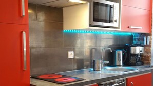 A kitchen with red cabinetry, a stainless steel dishwasher, a microwave, and a coffee maker. - Toulouse Canal du Midi (Toulouse)