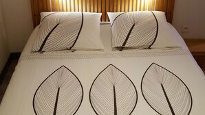 A bed with a leaf-patterned bedspread, wooden headboard, and a wall-mounted picture above. - Toulouse Canal du Midi (Toulouse)