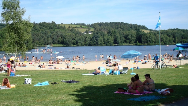 A beach with people sunbathing, swimming, and playing.