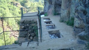 A stone staircase leading down a rocky path with a metal railing on one side.