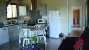 A compact kitchen with white appliances, a dining table with chairs, and a living area with a sofa.