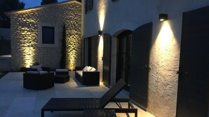 An outdoor patio with a stone wall, a lounge chair, and a sofa. - Bastide provençale 12 pers with swimming pool, 2 steps from Saint-Rémy-de-Pce (Eyragues)