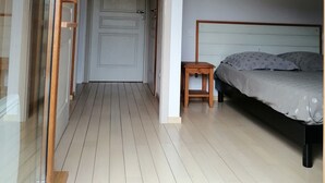 Ein Schlafzimmer mit einem Bett, einem kleinen Nachttisch und einer Tür zu einem anderen Raum.
