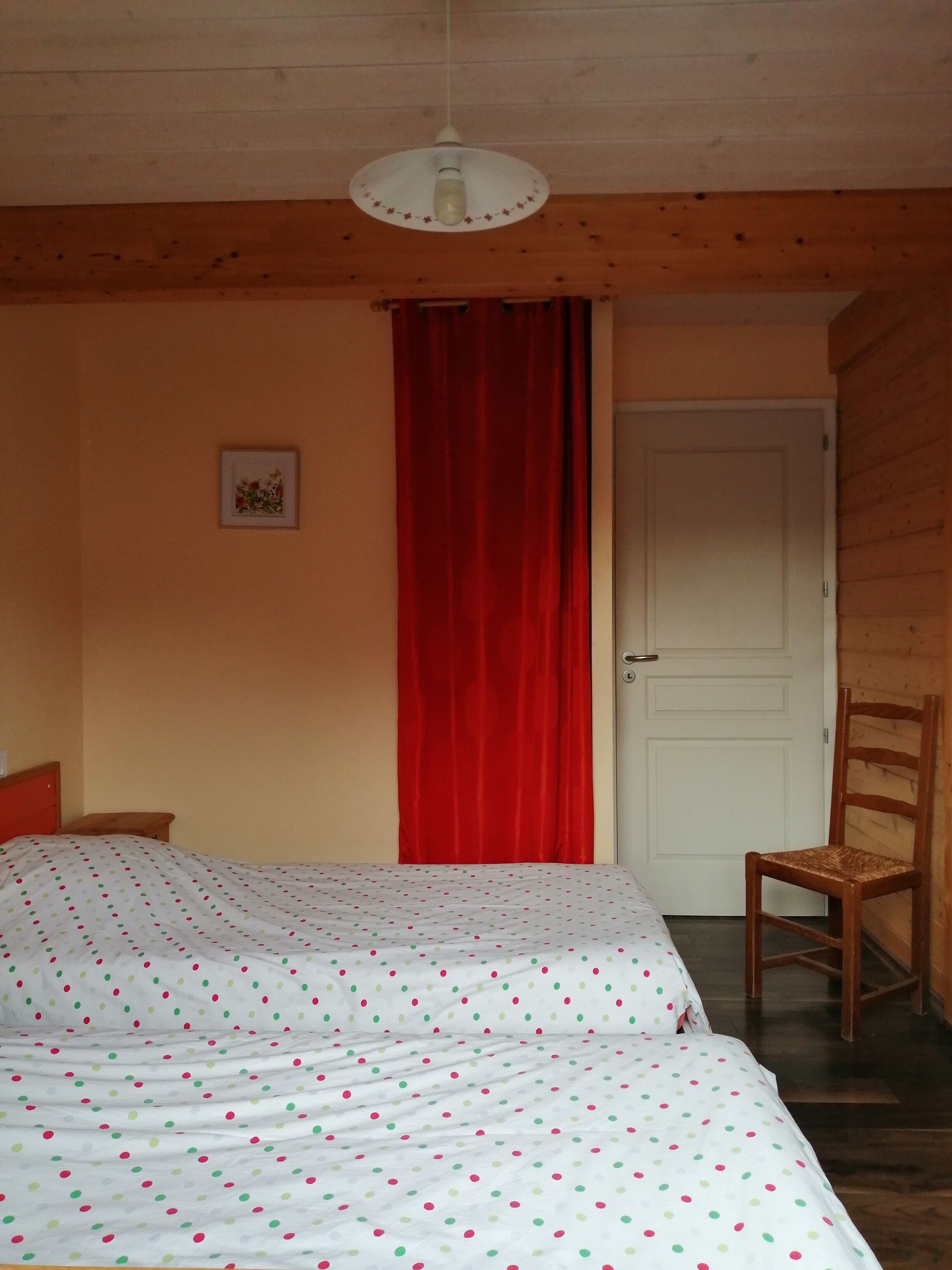 A bedroom with a bed, a chair, a door, and a light fixture.
