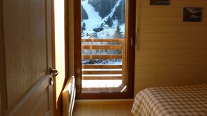Ein Zimmer aus Holz mit einem großen Fenster mit Blick auf eine verschneite Berglandschaft.