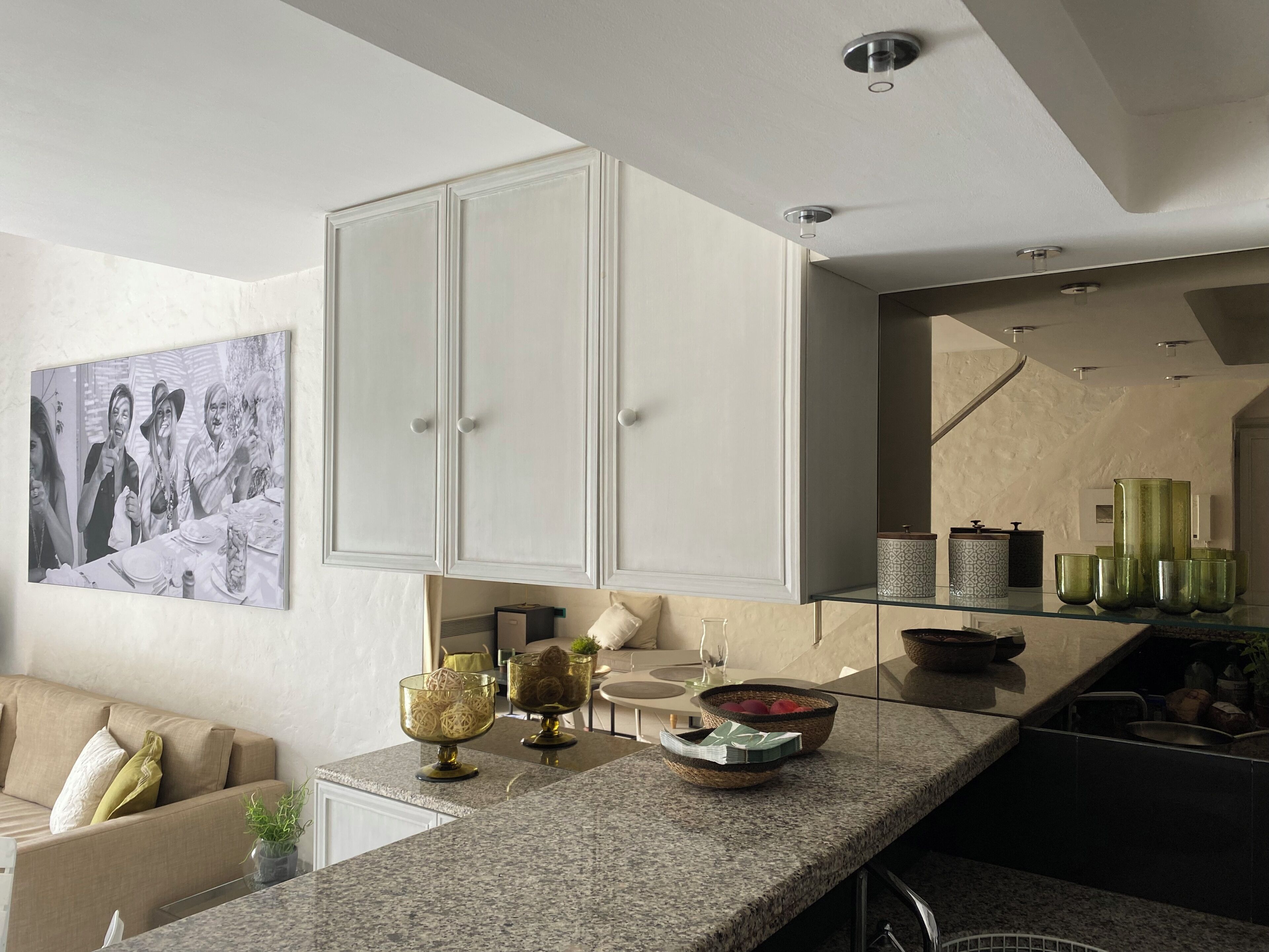 Een moderne keuken met een granieten aanrecht, witte kasten en een zithoek met een bank.