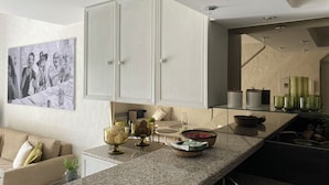 Una cocina moderna con encimera de granito, armarios blancos y un comedor con sofá.