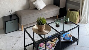 Una sala de estar moderna con un sofá, una mesita de centro con revistas, un cuadro en la pared y un equipo de aire acondicionado.
