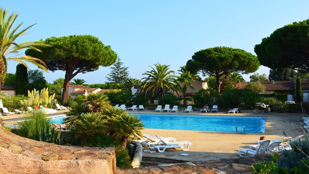 Zona de piscina con sillones de descanso y árboles.