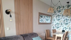Een moderne woonkamer met een grijze bank, twee kussens, een eettafel met stoelen en een ronde houten tafel.