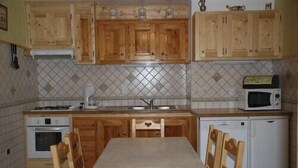 A kitchen with wooden cabinets, a tiled backsplash, a stove, a microwave, and a dishwasher. - 1st floor apartment in Savoyard chalet in Morzine. (Morzine)