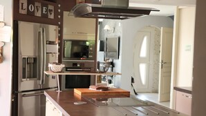 A modern kitchen with stainless steel appliances, a wooden countertop, and a hanging basket.
