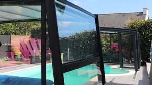 A swimming pool with a glass enclosure, surrounded by a wooden deck.