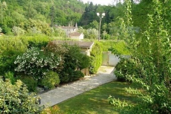 A garden pathway leading to a house surrounded by lush greenery.